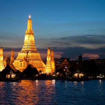 Wat Arun Tempel bei Nacht mit beleuchteter Prang am Chao Phraya-Fluss in Bangkok, Thailand.