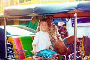 Vater und Sohn im TukTuk in den Straßen von Bangkok, Familienurlaub Thailand