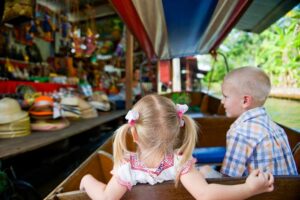 Kinder in einem Longtailboot auf dem Floating Market in dern Ancient City, Familienurlaub Thailand