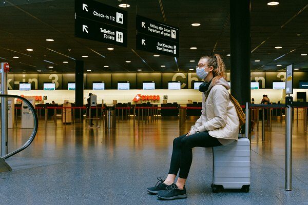 Eine Frau sitzt am Flughafen von Bangkok auf ihrem Koffer.