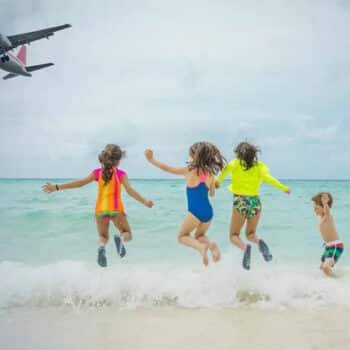 Kinder beim Spielen am Strand und ein Flugzeug befindet sich im Landeanflug auf Phuket