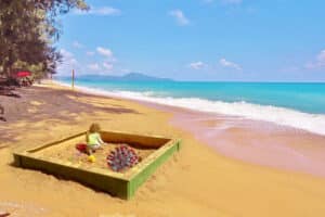 Ein Kind welches in einem Sandkasten am Strand von Phuket spielt.