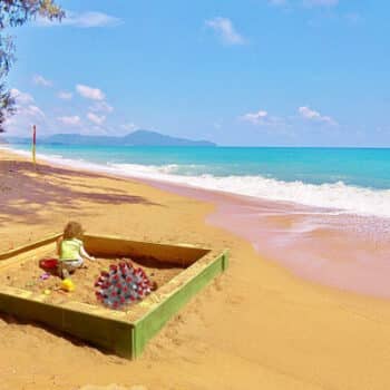 Ein Kind welches in einem Sandkasten am Strand von Phuket spielt.