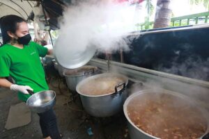 thailaenderin kocht ein klassisches Curry Gericht in riesigen Toepfen