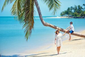 Mutter und kleiner Sohn am tropischen Strand sitzen auf einer Palme im Sommer Urlaub auf Koh Samui