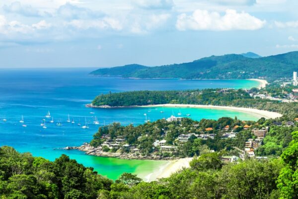 Wunderschöner türkisfarbener Ozean mit Wellen und Booten sowie eine Küste mit Stränden, aufgenommen vom Kata und Karon Strand Aussichtspunkt auf Phuket, Thailand