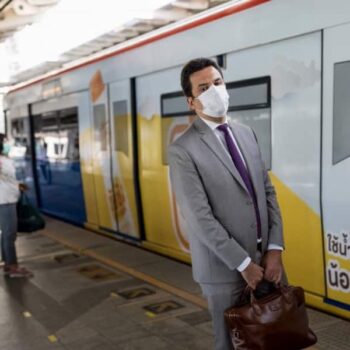 Ein thailaendischer Geschaeftsmann steht an einer BTS Skytrain Station in Bangkok, Thailand