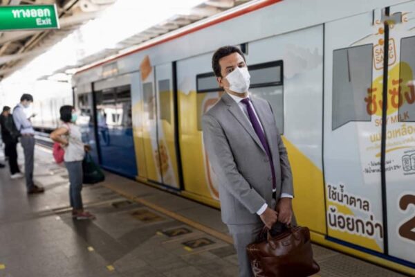 Ein thailaendischer Geschaeftsmann steht an einer BTS Skytrain Station in Bangkok, Thailand