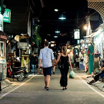 Touristen laufen Hand in Hand durch die abendlichen Gassen von Thailand