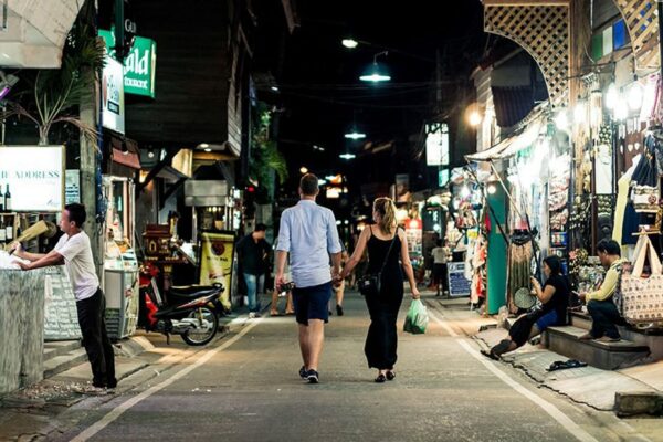 Touristen laufen Hand in Hand durch die abendlichen Gassen von Thailand