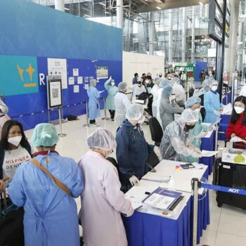 Touristen am Bangkoker Flughafen bei der Kontrolle der benötigten Papiere