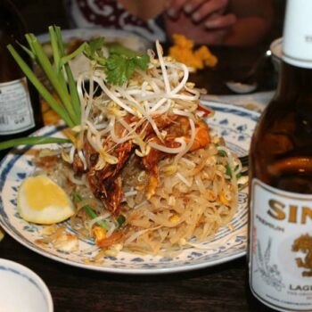 angerichtetes thailändisches Nudelgericht Pad Thai mit einer Flasche des bekannten Singha Bier