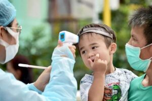 Temperaturkontrolle bei einem Baby, welches mit seinen Eltern in Bangkok gelandet ist.