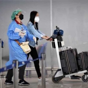Mitarbeiter des Bangkoker Flughafens beim Begleiten der Passagiere zu den Kontrollstationen.