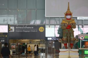 Eine thailaendische Statue am Flughafen Bangkok mit einer Maske vor dem Mund.