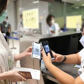 Eine Beamtin der Immigration scannt den Thailand Pass QR Code einer einreisenden Touristin.