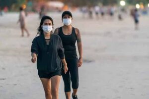 2 Damen die am Strand laufen und dabei eine Maske tragen, Thailand