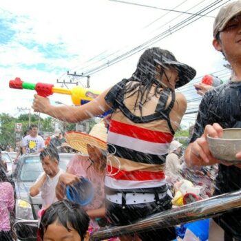 Thailänder die dem Brauch der Wasserschlacht am Songkran folgen und sich eine Wasserschlacht auf den Straßen liefern.
