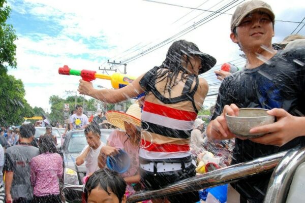 Thailänder die dem Brauch der Wasserschlacht am Songkran folgen und sich eine Wasserschlacht auf den Straßen liefern.