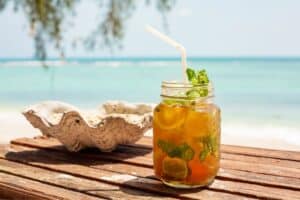 Ein Mai Thai Cocktail am Strand serviert mit BLick über das türkisblaue Meer.