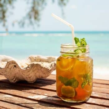 Ein Mai Thai Cocktail am Strand serviert mit BLick über das türkisblaue Meer.