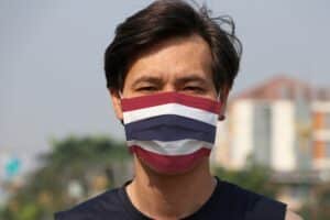 Ein Thailänder mit einem Mundschutz in den Farben der thailändischen Nationalflagge.