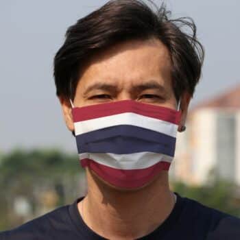 Ein Thailänder mit einem Mundschutz in den Farben der thailändischen Nationalflagge.