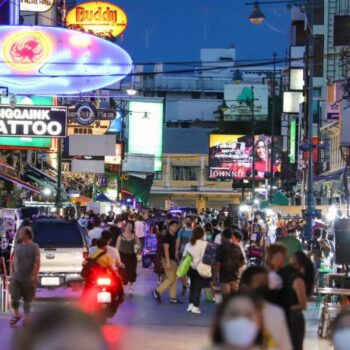 Neonlichter erhellen die Khao San Road nach Einbruch der Dunkelheit, wenn immer mehr Kneipen, Restaurants und Imbissbuden ihr Geschäft betreiben und die Menschen auf die Straße locken. 