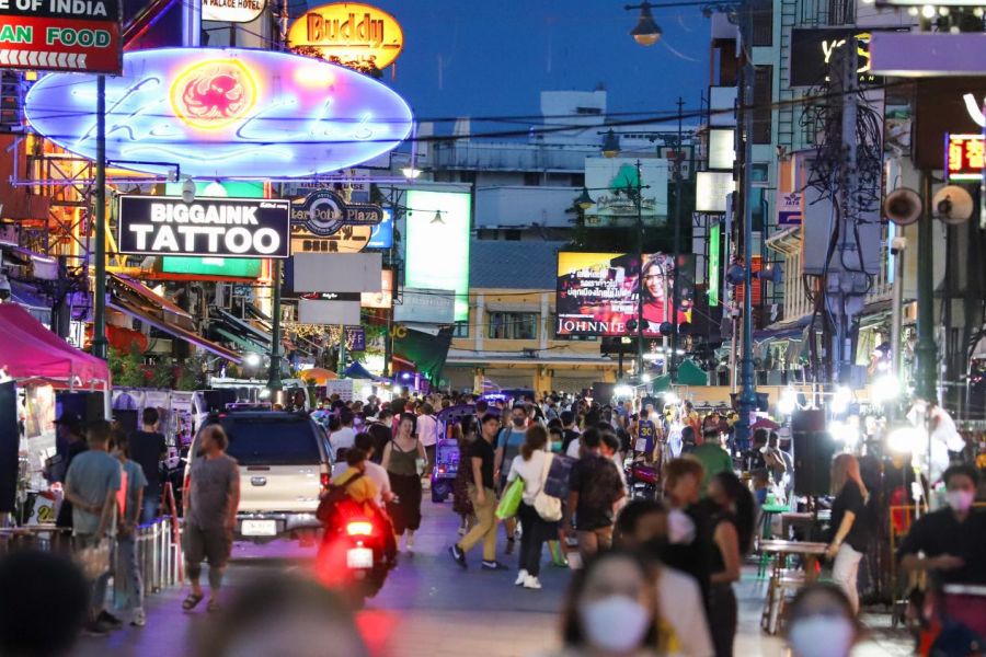 Neonlichter erhellen die Khao San Road nach Einbruch der Dunkelheit, wenn immer mehr Kneipen, Restaurants und Imbissbuden ihr Geschäft betreiben und die Menschen auf die Straße locken. 