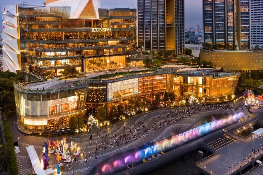 Beleuchtetes ICONSIAM am Chao Phraya in der Dämmerung, davor die farbig angestrahlten Fontänen der Wassershow und Zuschauer an der Uferpromenade