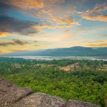 Panoramablick über einen der Nationalparks in Thailand mit üppigem Grün, einem Fluss und einem beeindruckenden Sonnenuntergangshimmel.