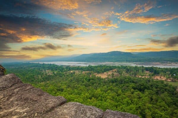 Panoramablick über einen der Nationalparks in Thailand mit üppigem Grün, einem Fluss und einem beeindruckenden Sonnenuntergangshimmel.