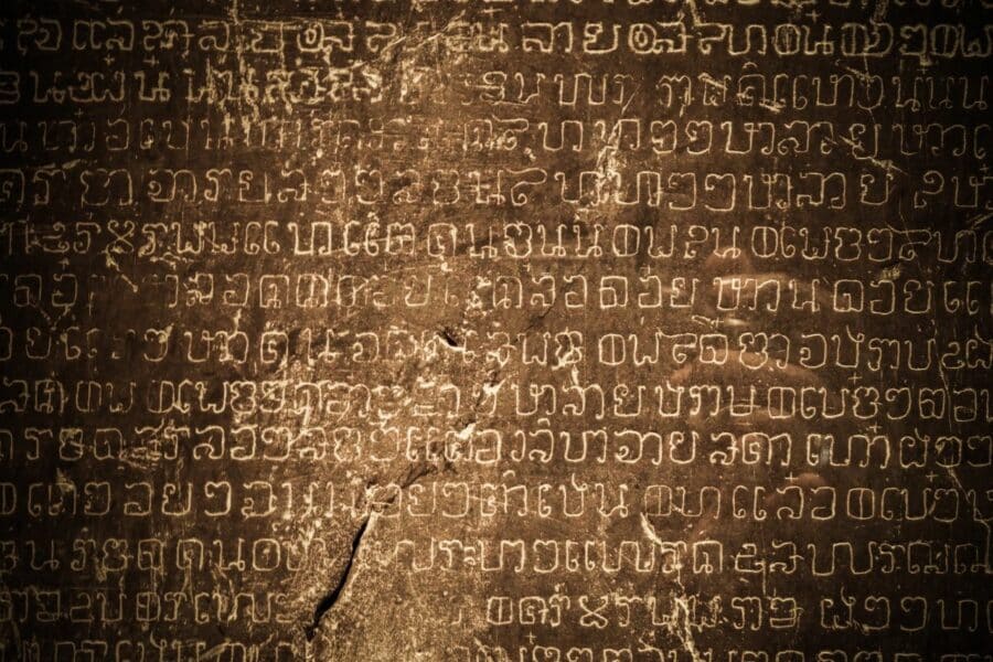 Nahaufnahme einer antiken thailändischen Schrift, die in Stein gemeißelt ist, und die reiche Geschichte Thailands zeigt.