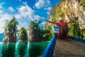 Reisender auf einem Longtailboot am Cheow Lan See im Khao Sok Nationalpark mit Kalksteinfelsen, Thailand