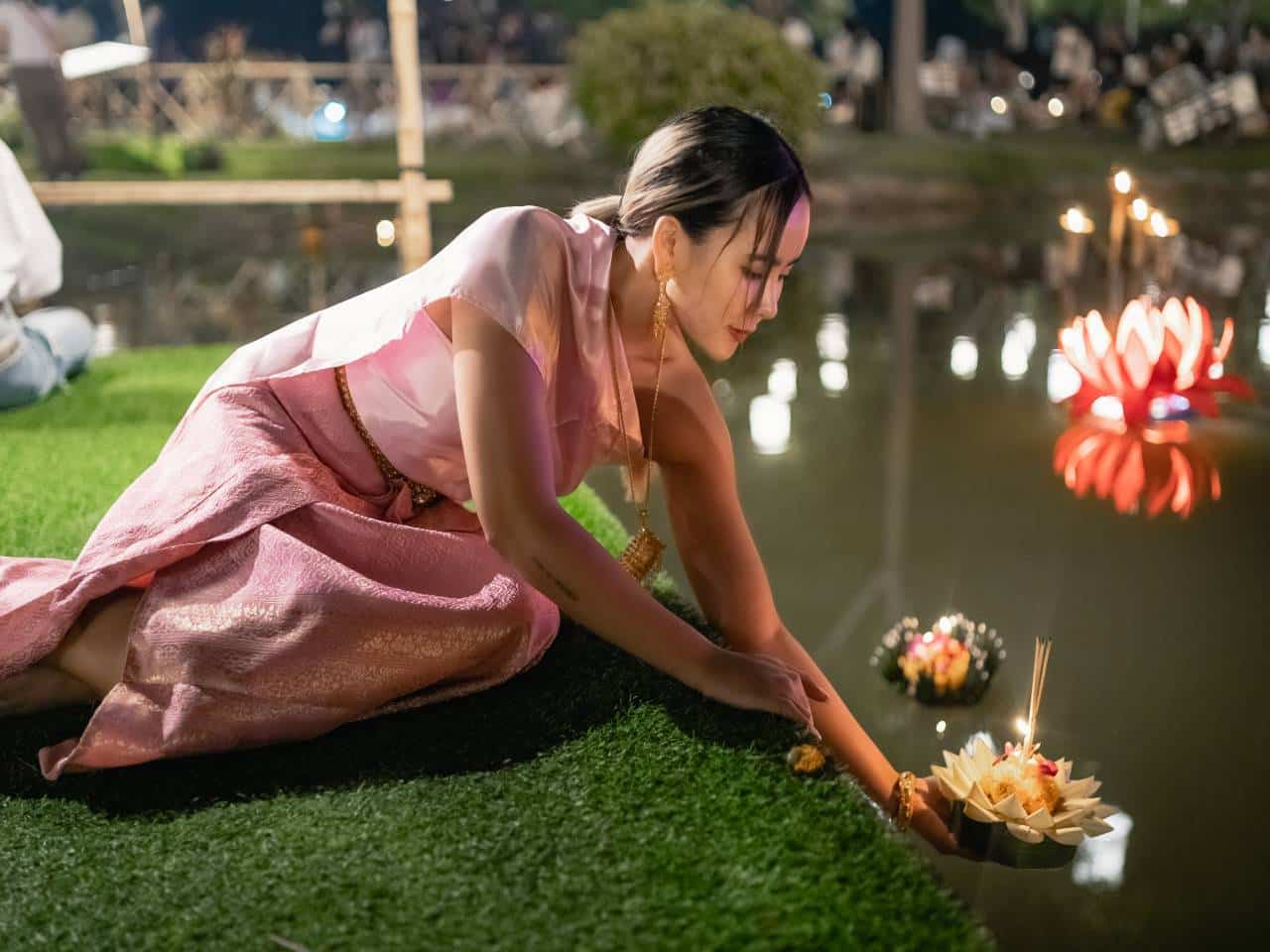 Teilnehmerin setzt beim Loy Krathong Festival in Chiang Mai einen traditionellen Krathong auf das Wasser