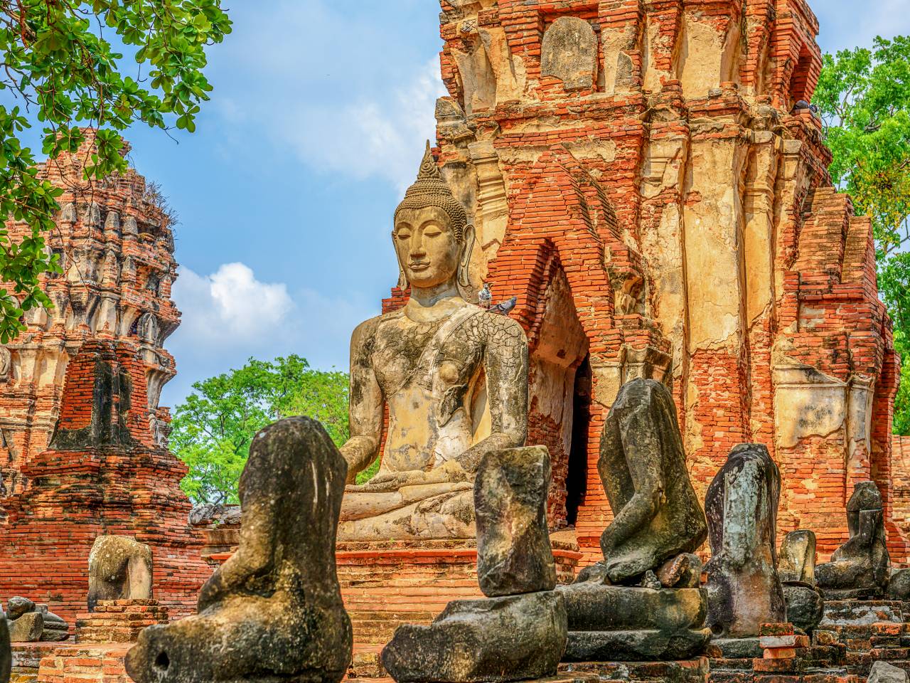 Historische Buddha-Statue zwischen den Tempelruinen von Ayutthaya während einer Loy Krathong Rundreise durch Thailand