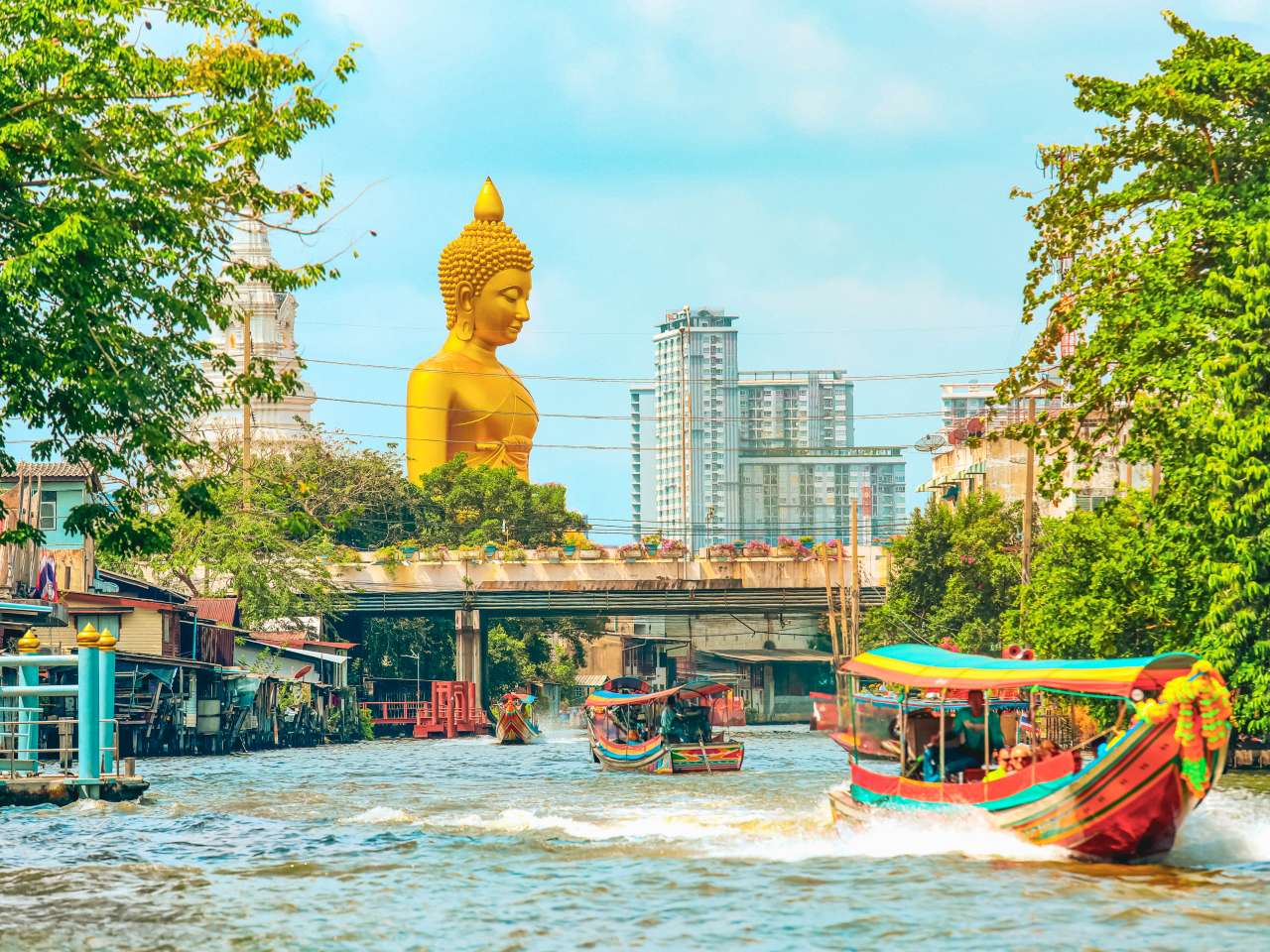 Longtailboote auf einem Khlong in Bangkok mit großem Buddha im Hintergrund