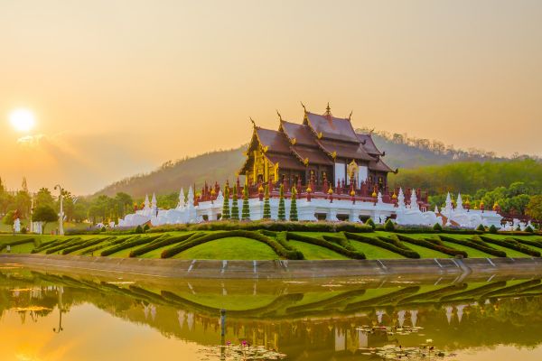 Der Königliche Pavillon Ho Kham Luang im Royal Park Rajapruek bei Chiang Mai spiegelt sich im Wasser bei Sonnenuntergang