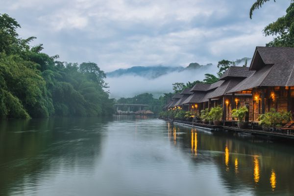 Raft Resort mit traditionellen Holzbungalows auf dem Fluss im nebelverhangenen Dschungel Zentralthailands